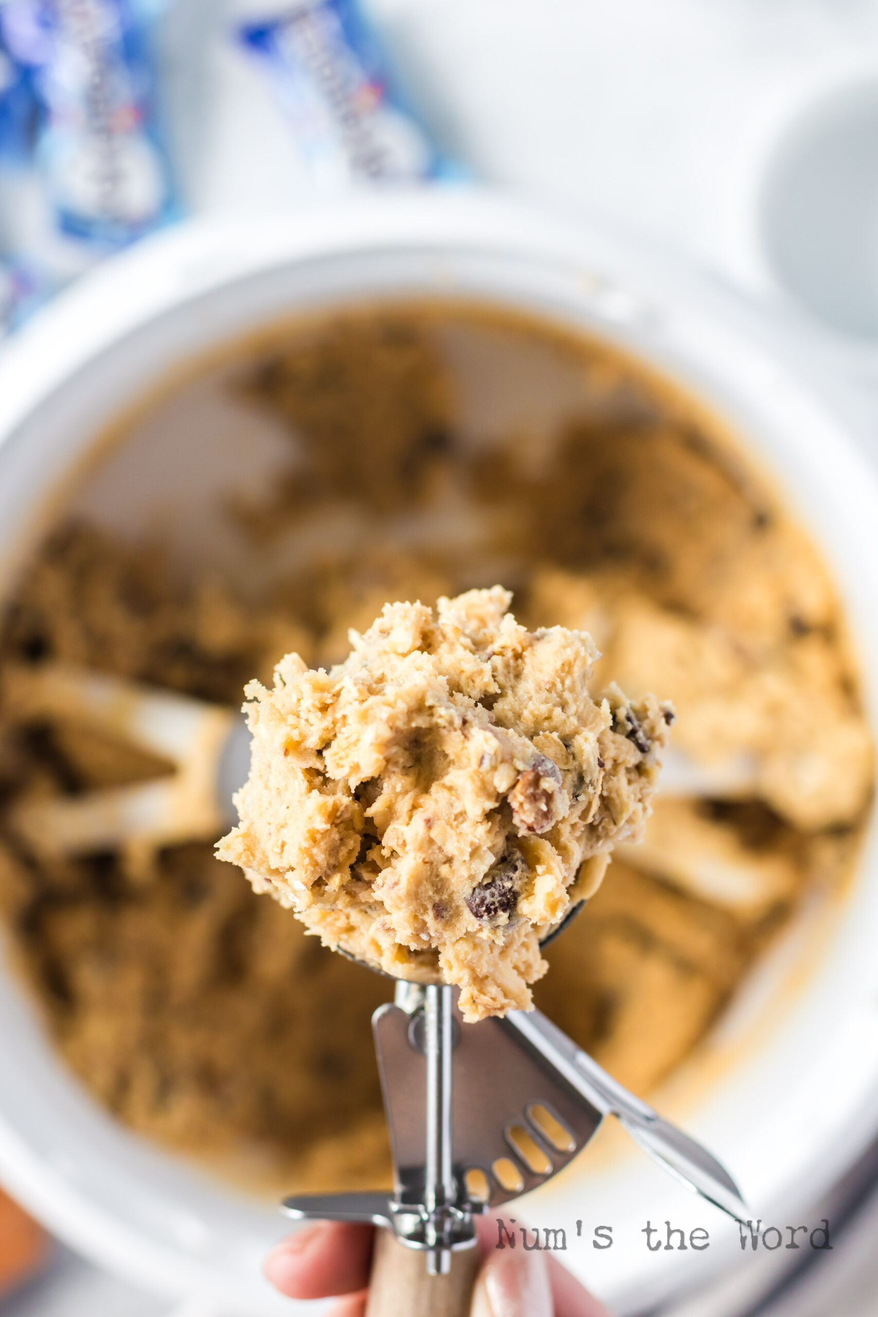 cookie scoop full of dough over cookie dough bowl