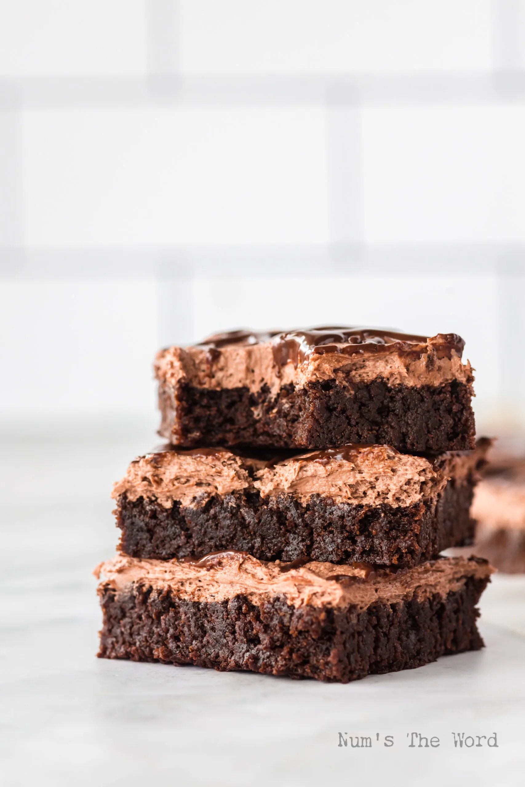 side view of 3 brownies stacked on top of each other. The top brownie has a bite removed.