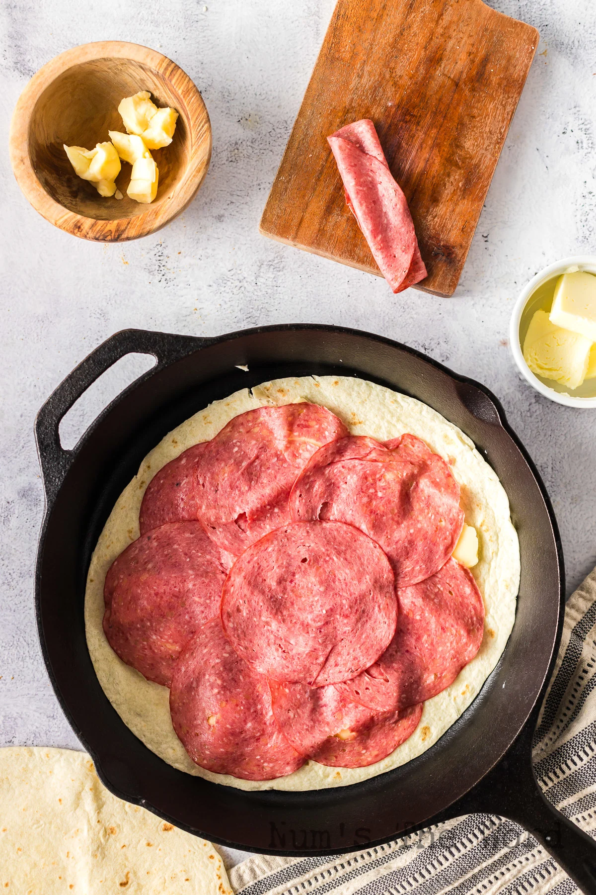 Tortilla in skillet topped with cheese curds and corned beef slices