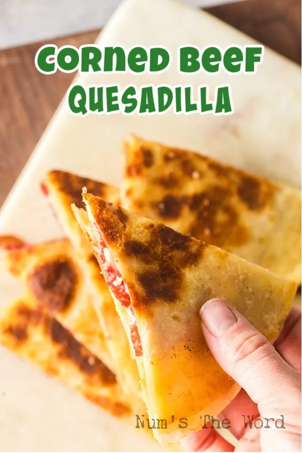 Main image for Corned Beef Quesadilla. Hand holding a triangle.