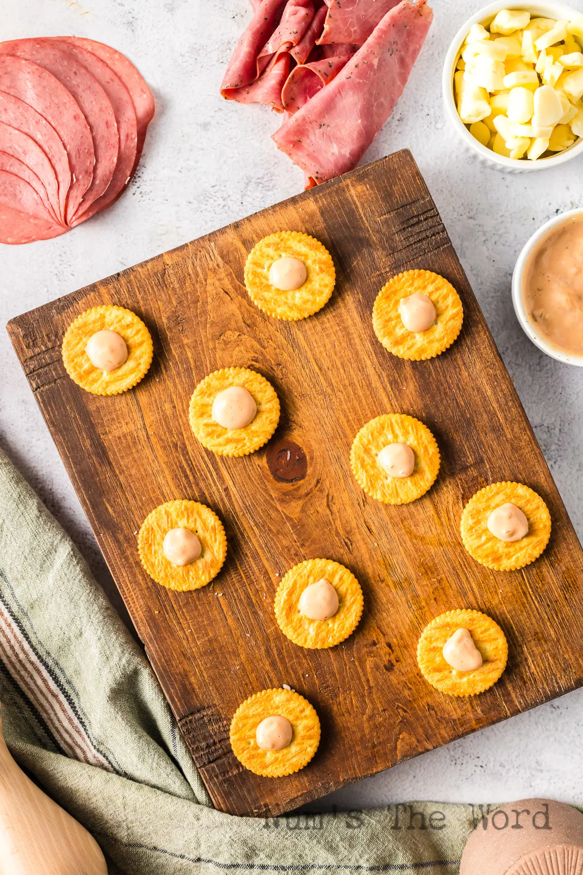 crackers laid out on board with a dollop of dressing on each cracker.