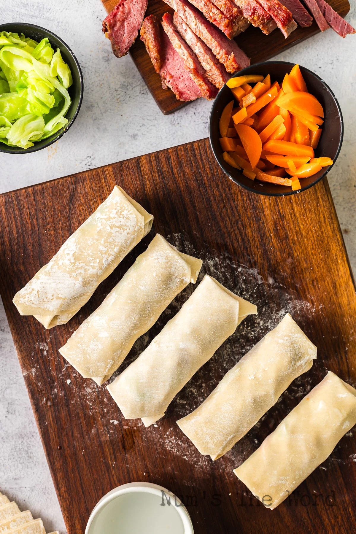 5 wrapped up egg roll wrappers filled and ready to cook.