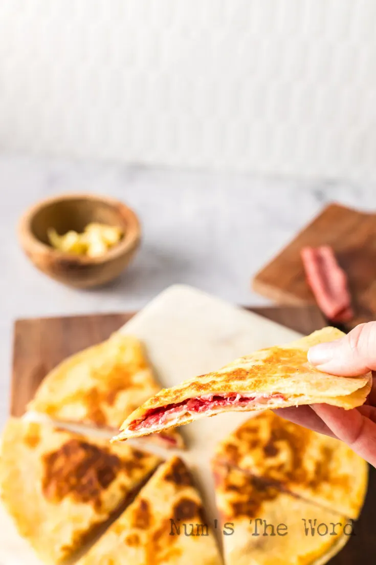 hand holding a slice of quesadilla up