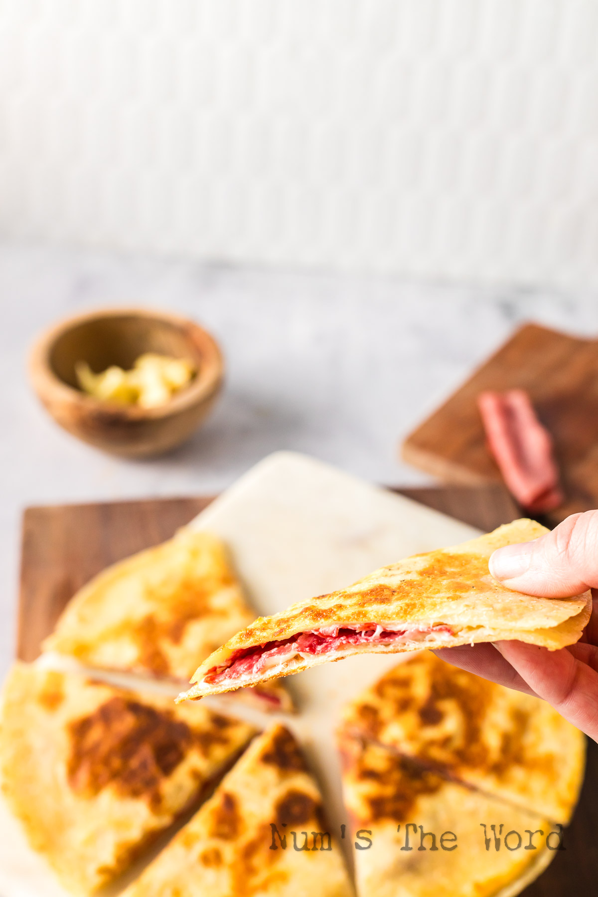 hand holding a slice of quesadilla up