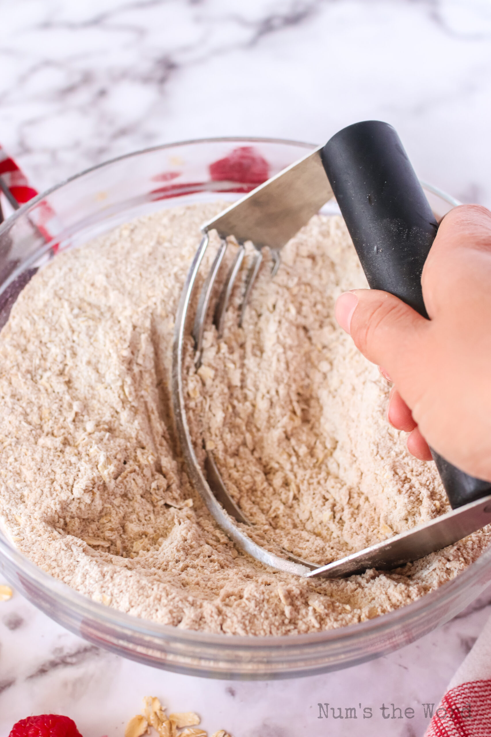 A pastry blender mixing butter into flour and oats
