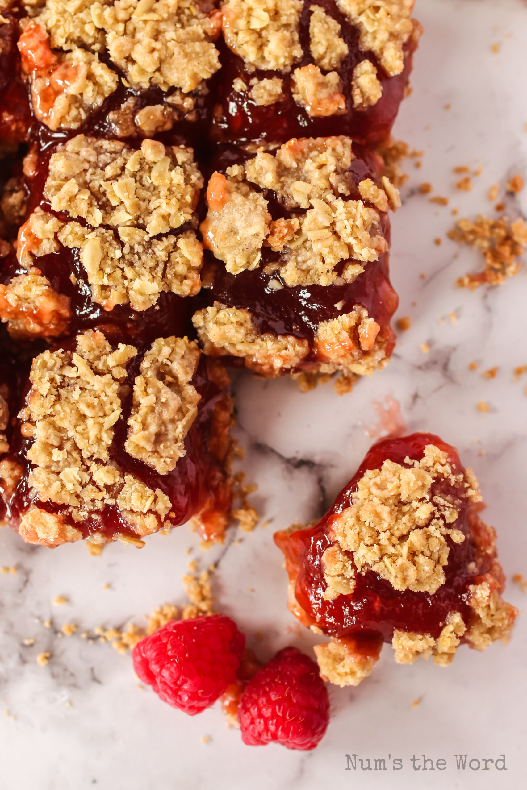 image of raspberry bars on counter with a few raspberries