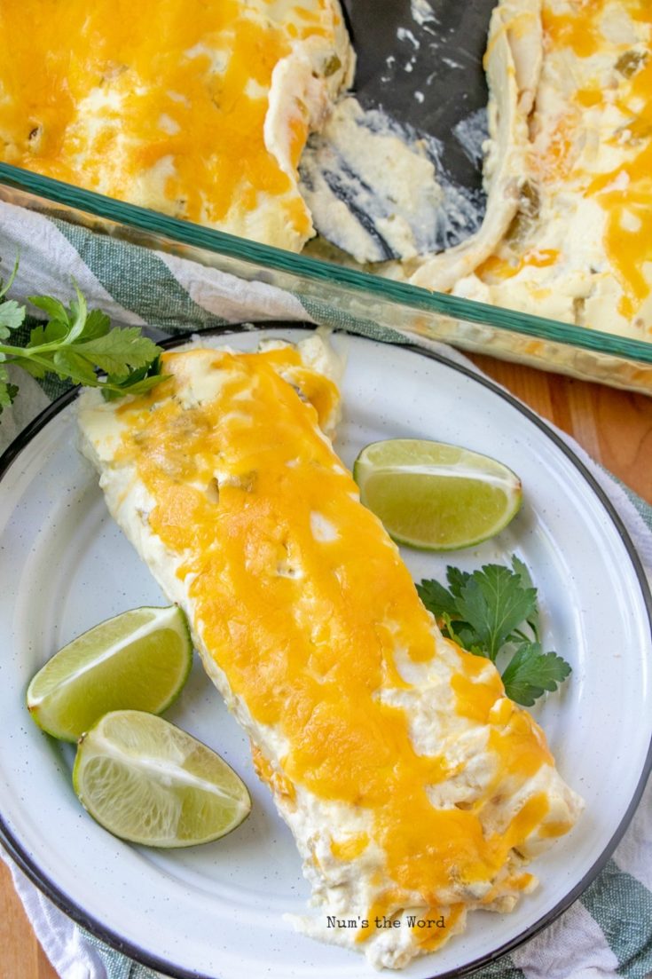 Cheesy Chicken Enchiladas - enchiladas on plate with lime wedges and cilantro