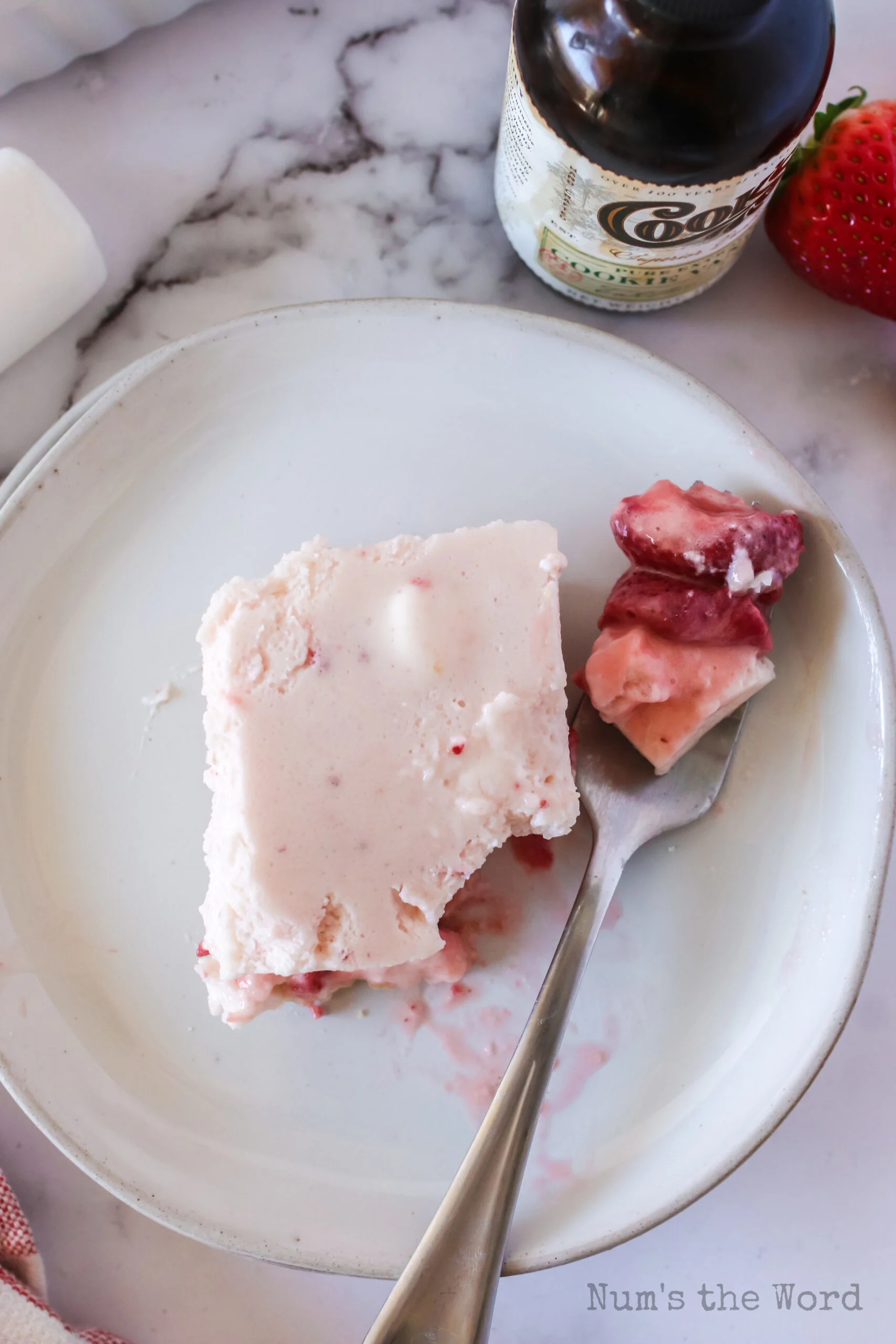 a no bake strawberry bar square on plate with a forkful. Photo taken from the top looking down