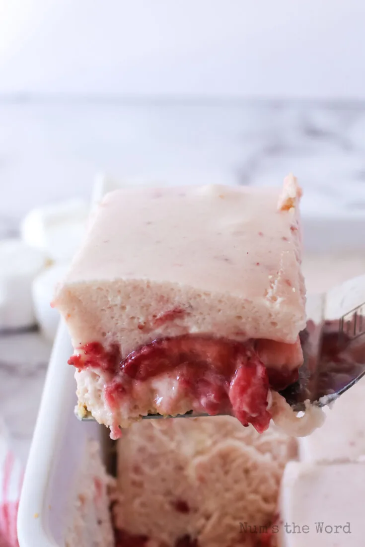 spatula scooping a portion of the strawberry crumb bar out of pan.