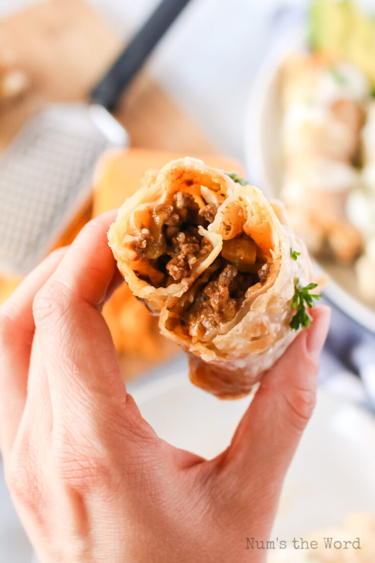 hand holding a beef chimichanga cut in half to show filling