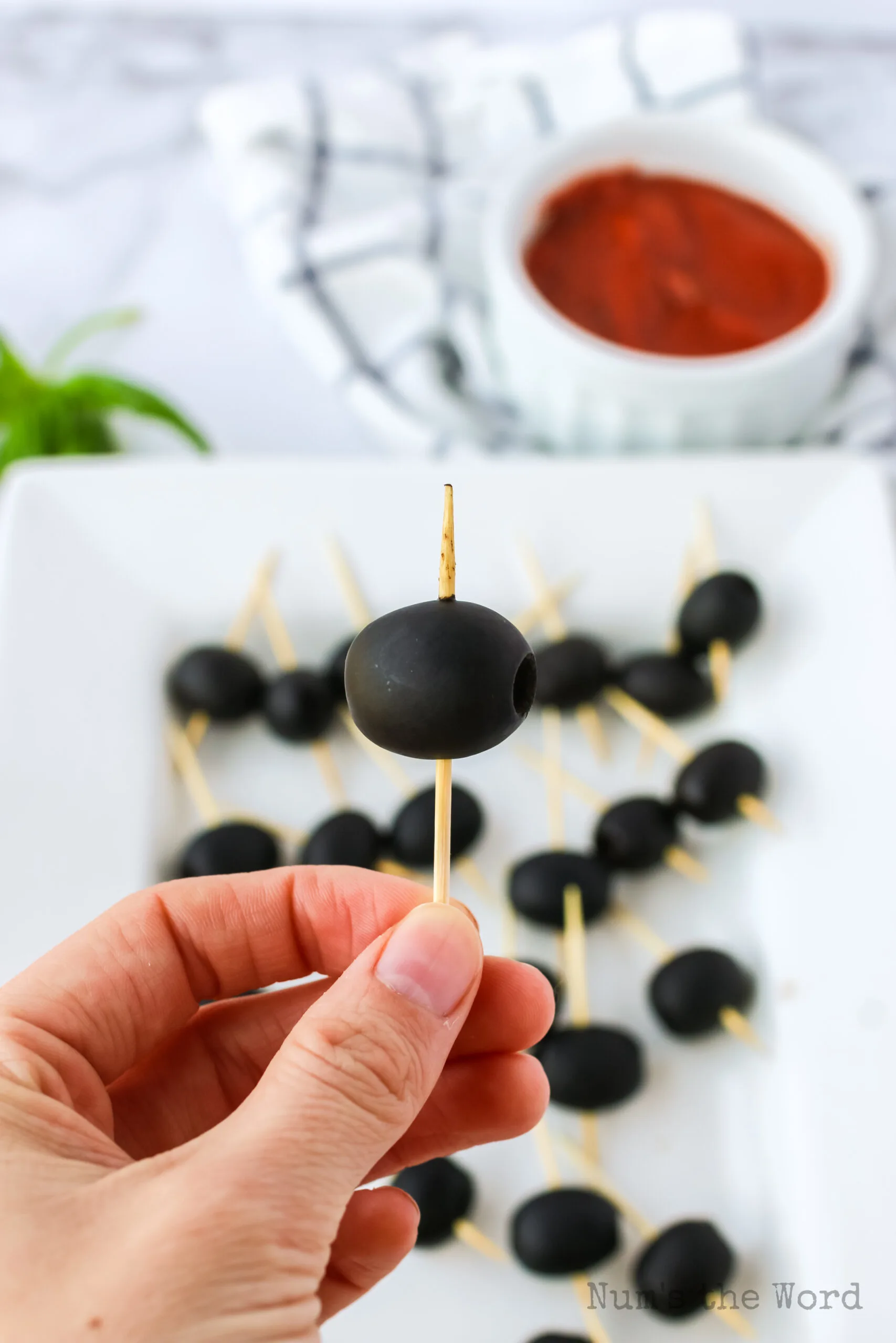 Toothpick with a black olive on the end