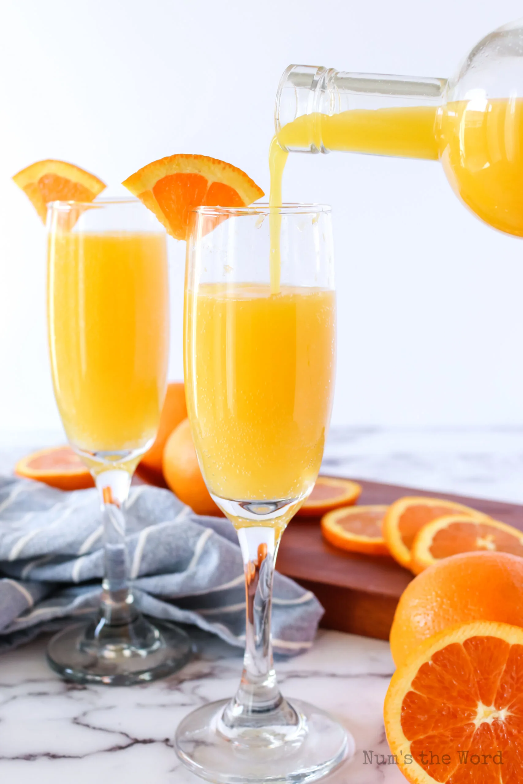 orange juice being poured into a glass full of ginger ale.