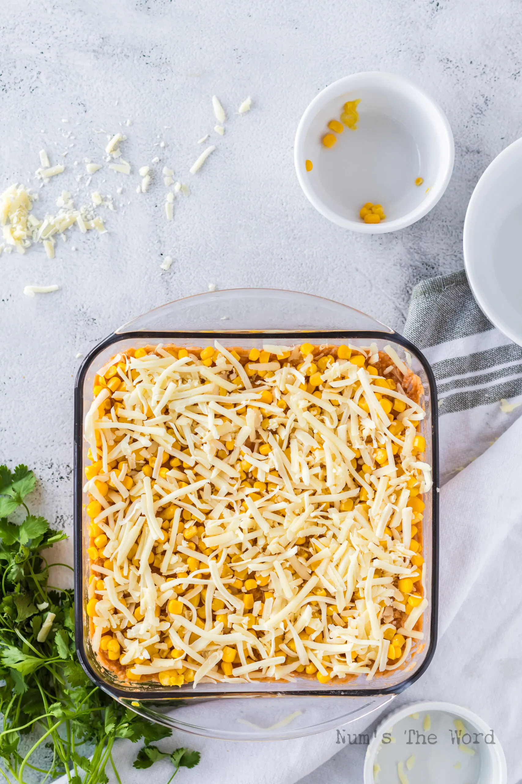 Chicken and Rice Casserole with refried beans in dish with corn and cheese on top.