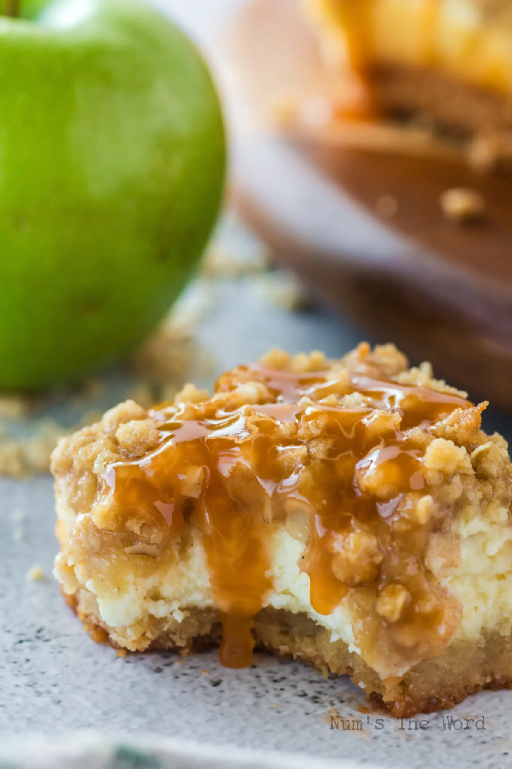 1 caramel apple cheesecake bar on counter with a bite removed.