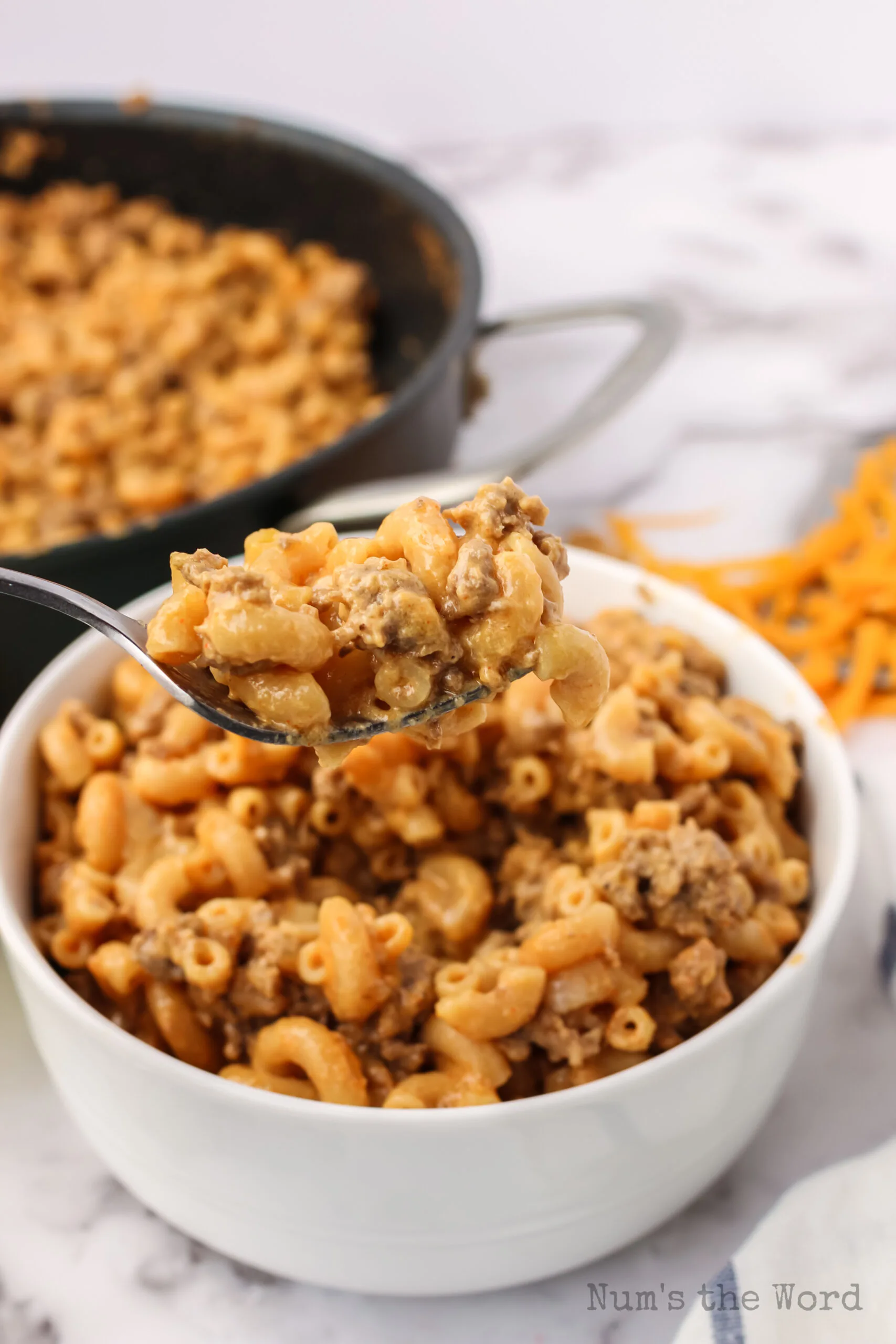 Cheesy Hamburger Helper in bowl with a spoon scooping a portion out