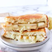 front view of brie grilled cheese sandwich cut in half with melted cheese and warm pears.