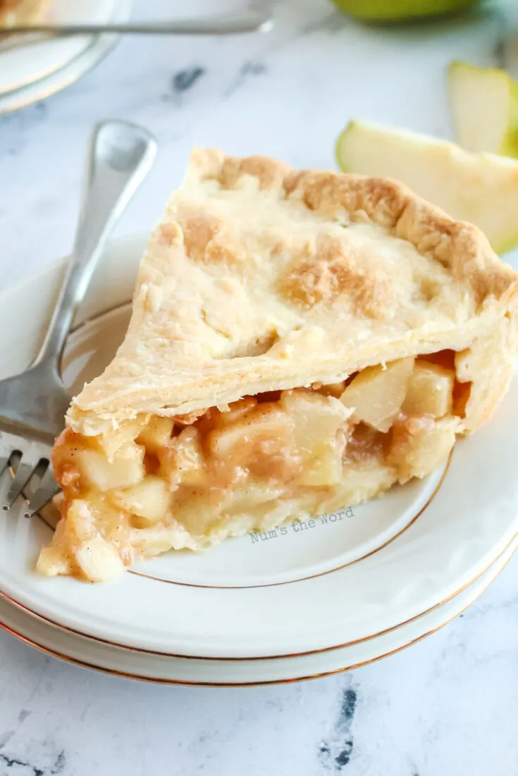 slice of pear pie on a plate, showing juice pears in cinnamon sauce ready to be eaten - zoomed in image.