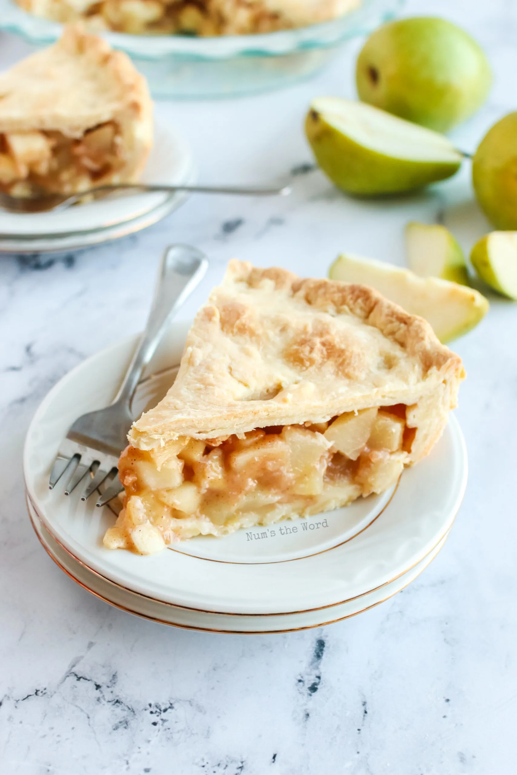 A slice of pear pie on a plate ready to be eaten - zoomed out image