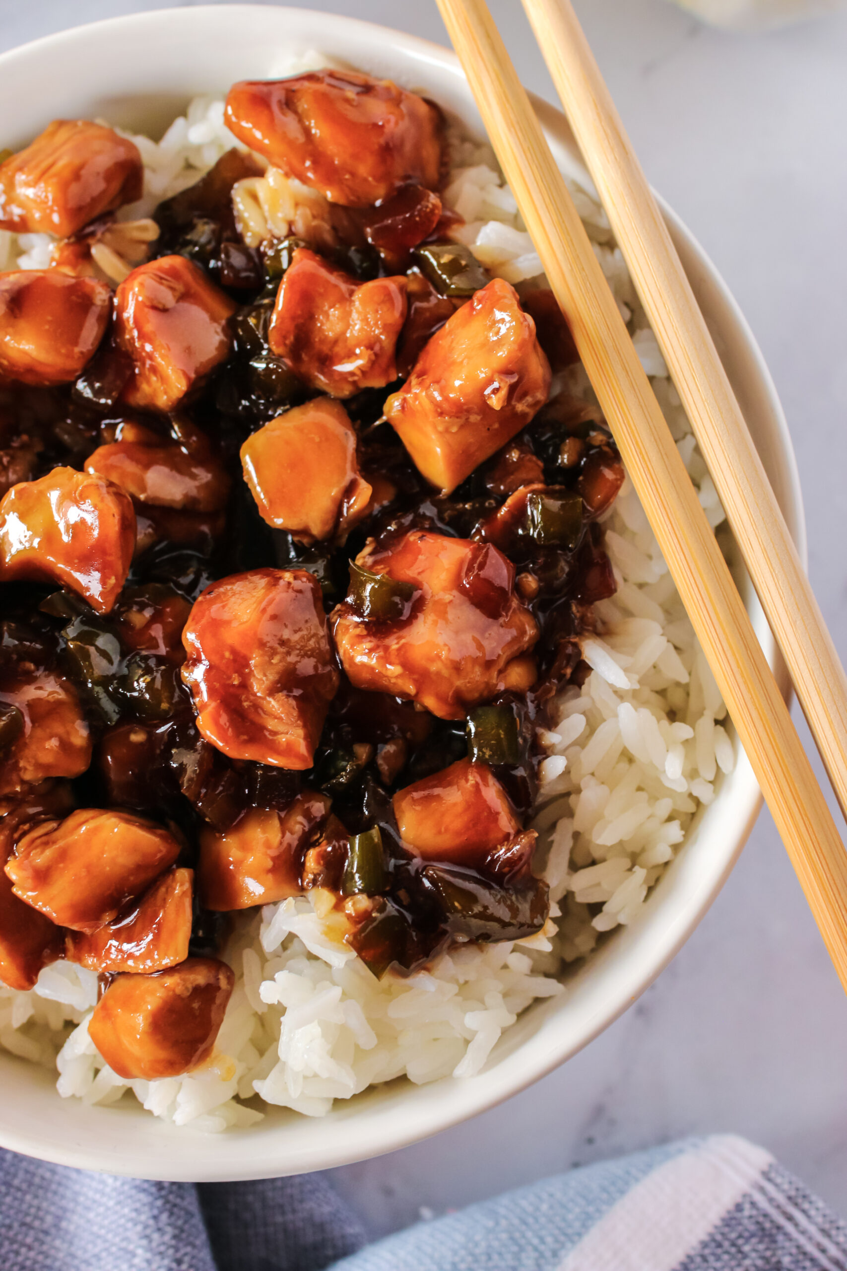 zoomed in image of chicken in bowl with rice and chop sticks