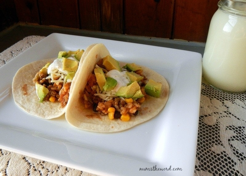 One Pot Mexican Taco Filling - two soft tacos on a plate topped with sour cream and avocado