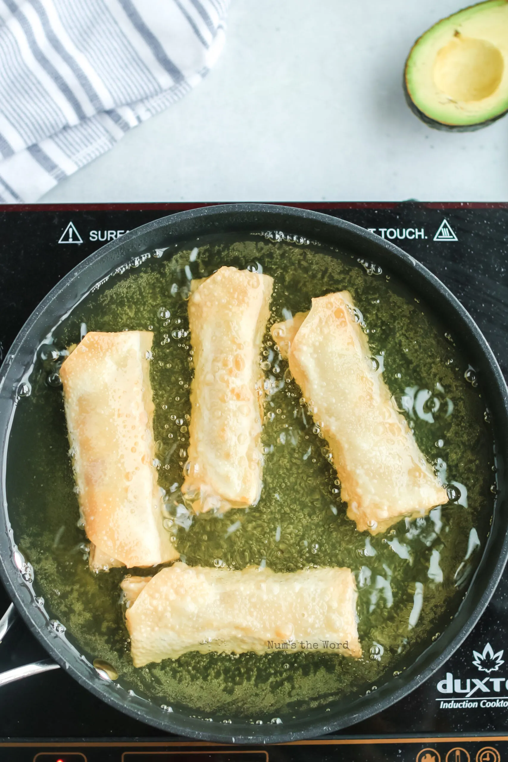 egg rolls being fried in oil in a skillet