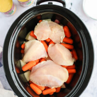 4 chicken breasts placed on top of carrots and potatoes.