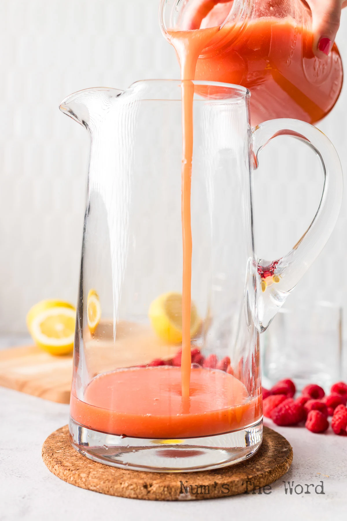raspberry puree mixture added to a glass pitcher.