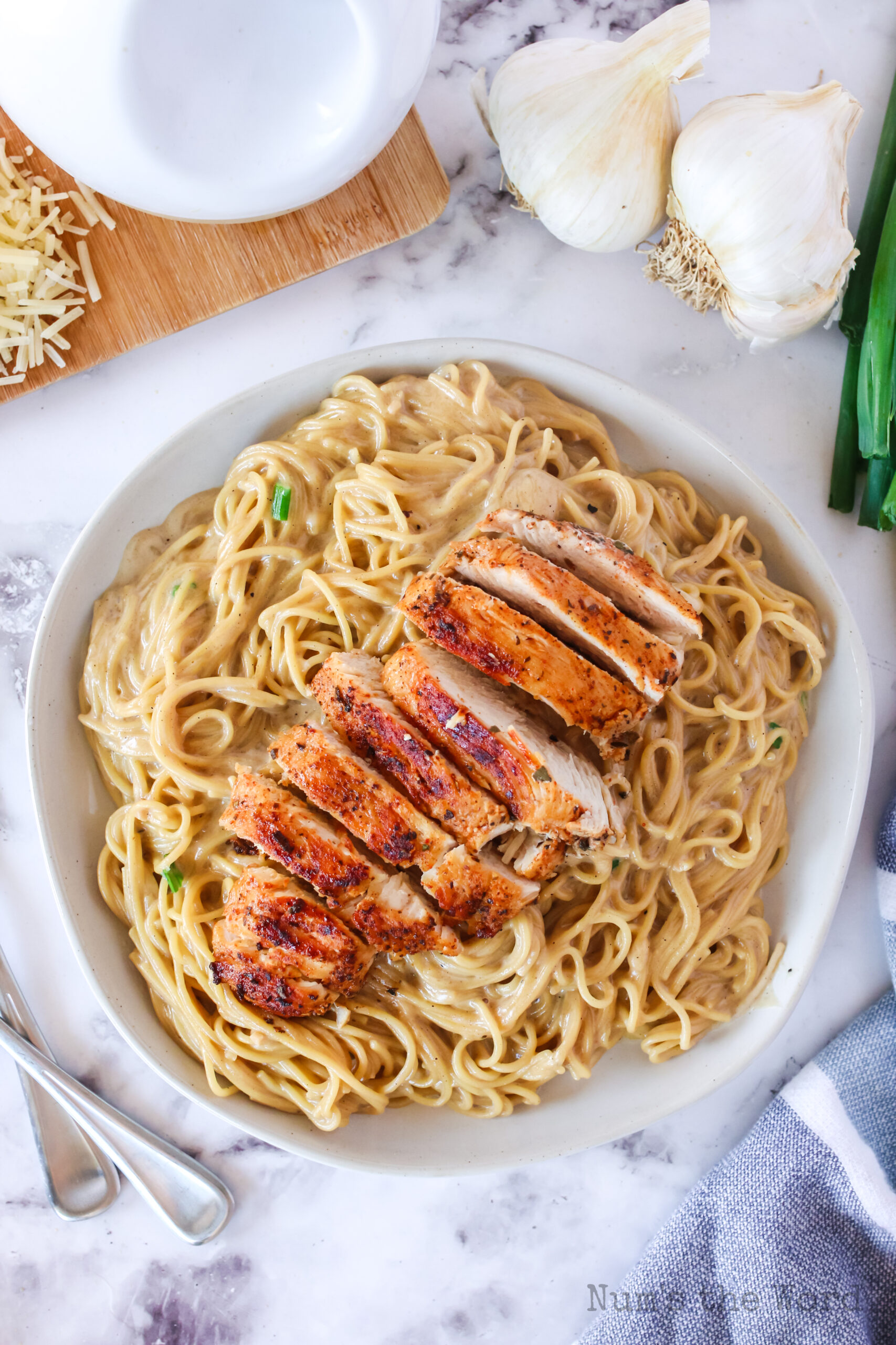 zoomed out image of sliced chicken breast on a bed of creamy pasta