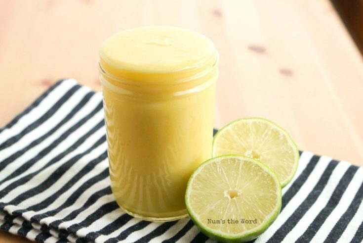Homemade Lime Curd - side view of lime curd in glass jar with sliced limes next to it.