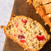 Slice of cherry coconut bread on cutting board.