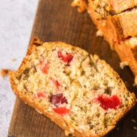 Slice of cherry coconut bread on cutting board.