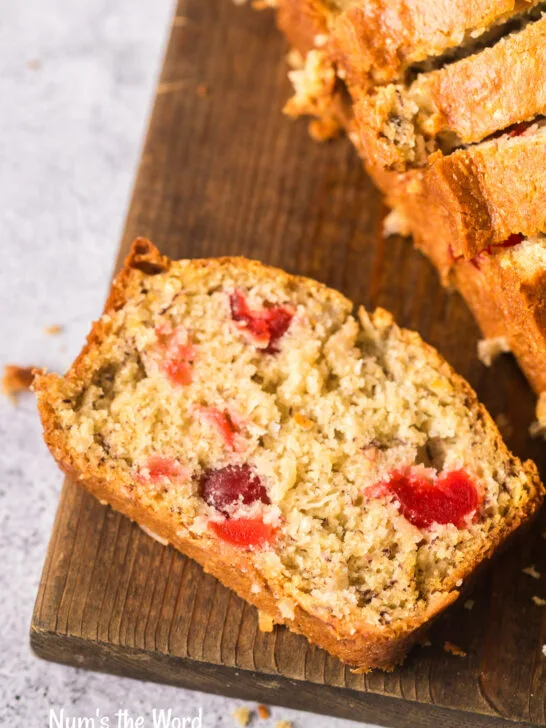 Slice of cherry coconut bread on cutting board.