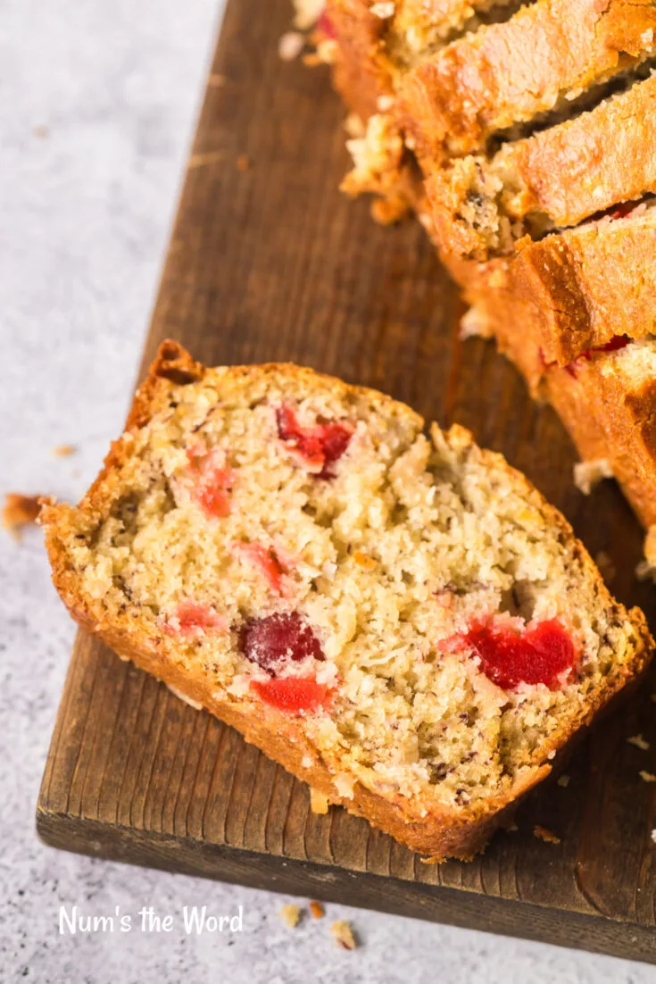 Slice of cherry coconut bread on cutting board.