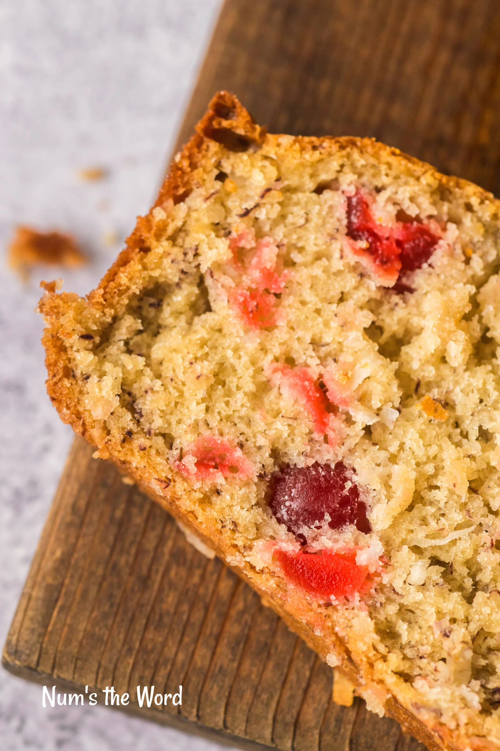 zoomed in image of bread on cutting board showing cherries inside.