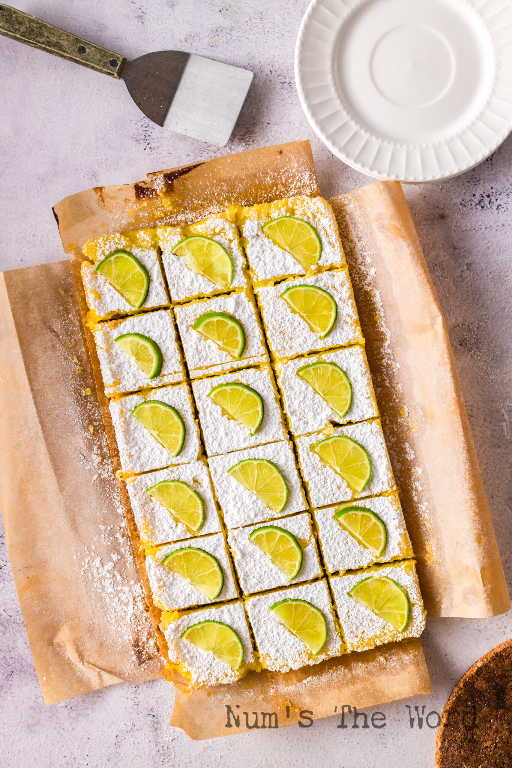 Bars laid out on a cutting board, cut and a half slice of lime on each piece.