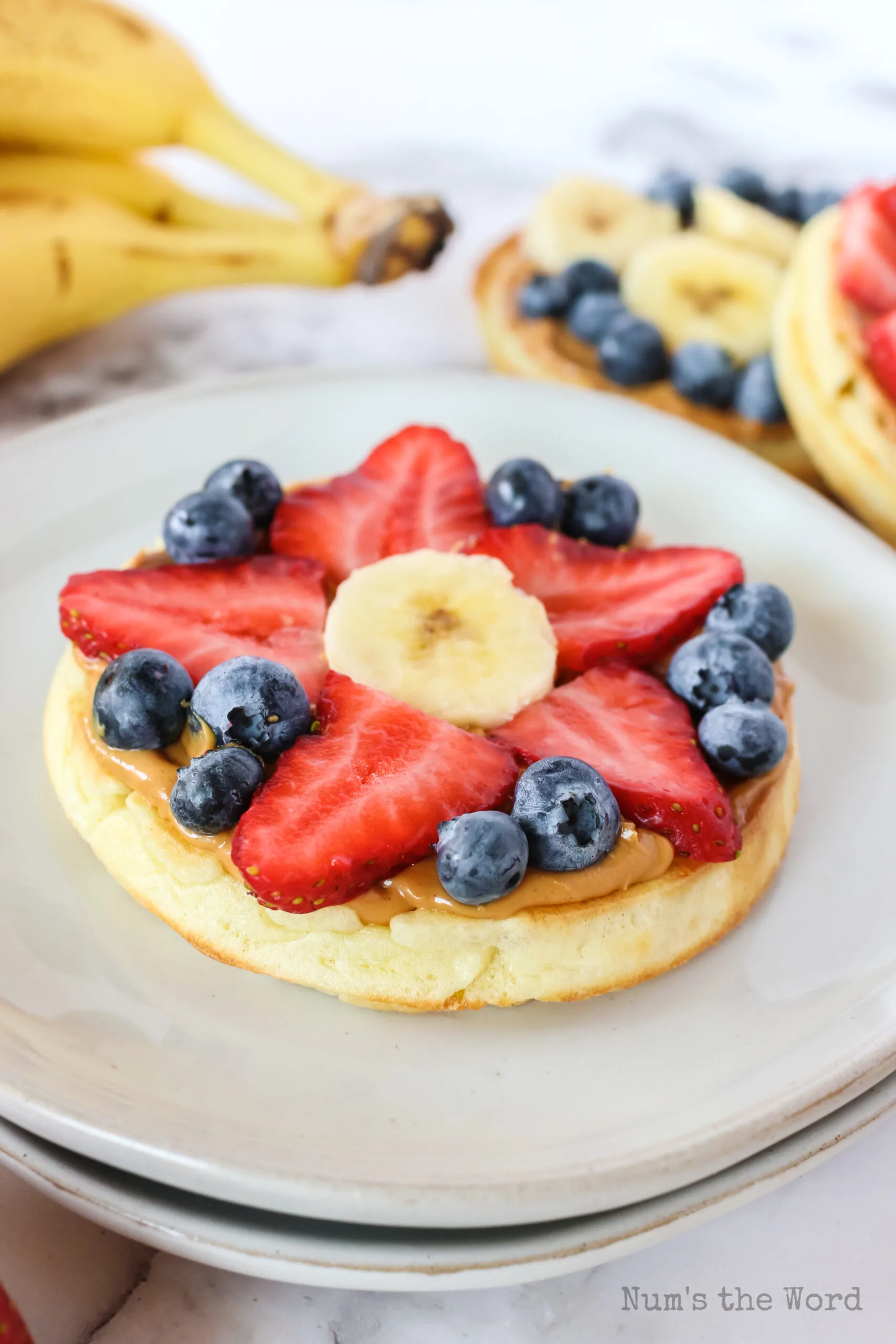 side view of single waffle with strawberries, blueberries and a banana slice.