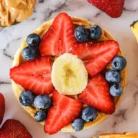 eggo pizza with blueberries, strawberries and banana in the shape of a flower.