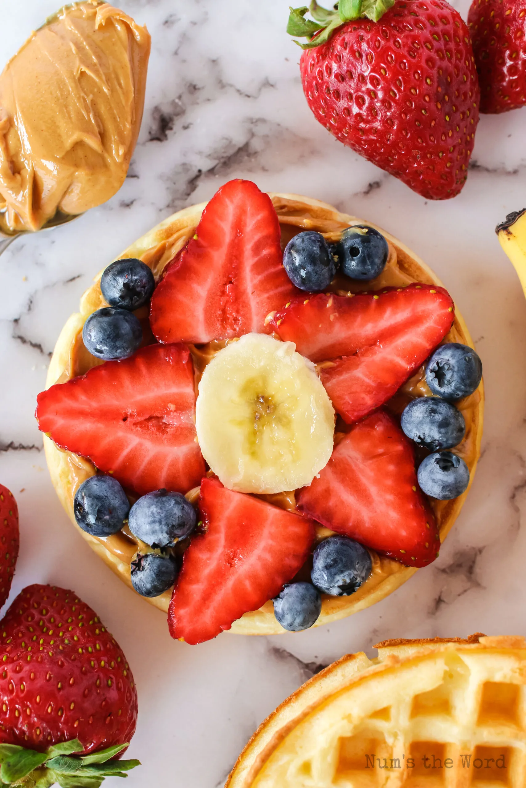 eggo pizza with blueberries, strawberries and banana in the shape of a flower.