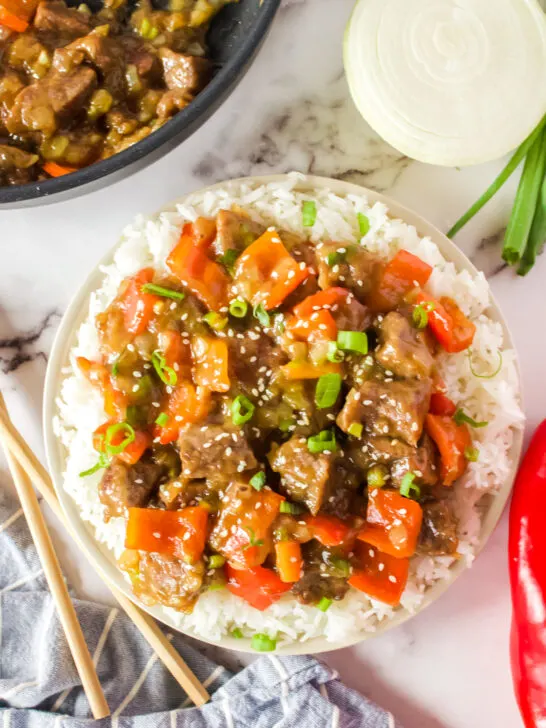 pepper steak over rice with sesame seeds sprinkled on top.