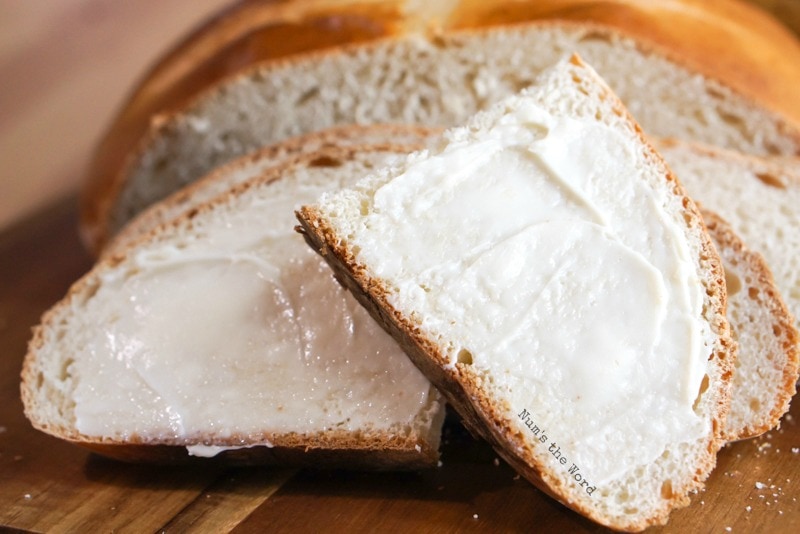 Banana Yeast Bread - One slice cut in half and smeared in butter in front of loaf.