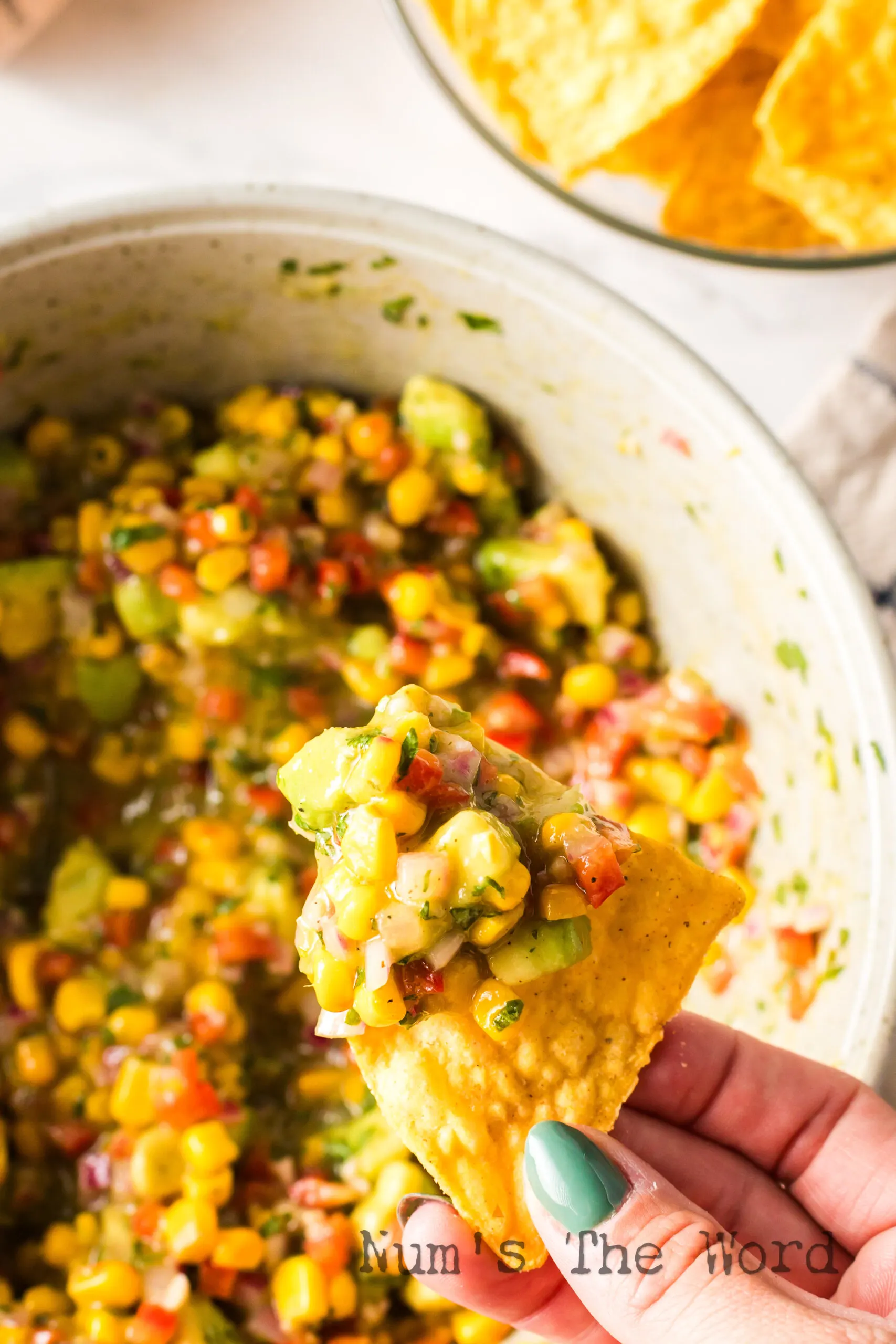 hand scooping salsa out of bowl