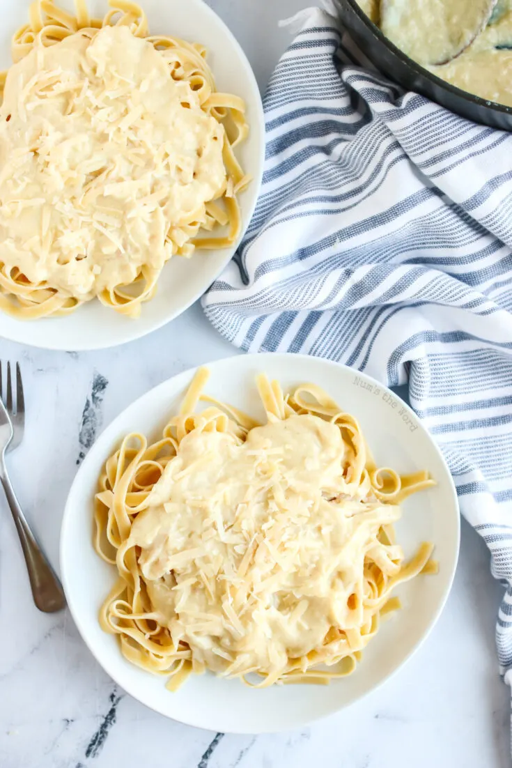 two plates of fettuccine alfredo ready to be eaten.