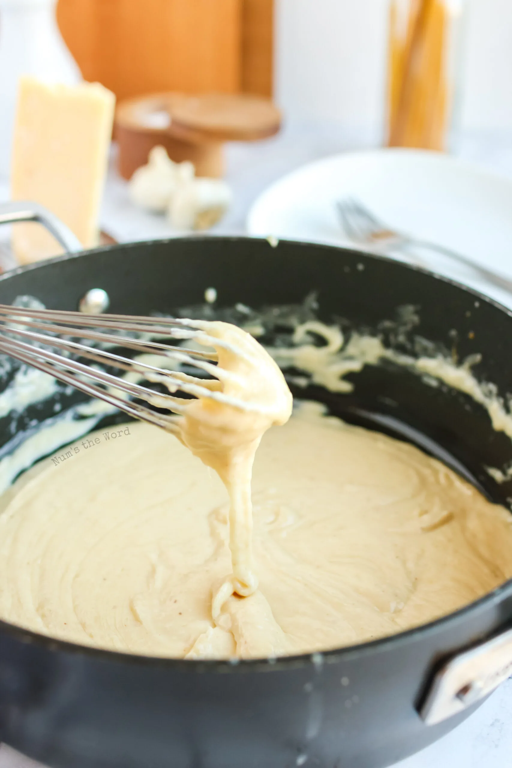 whisk showing how thick the alfredo sauce is