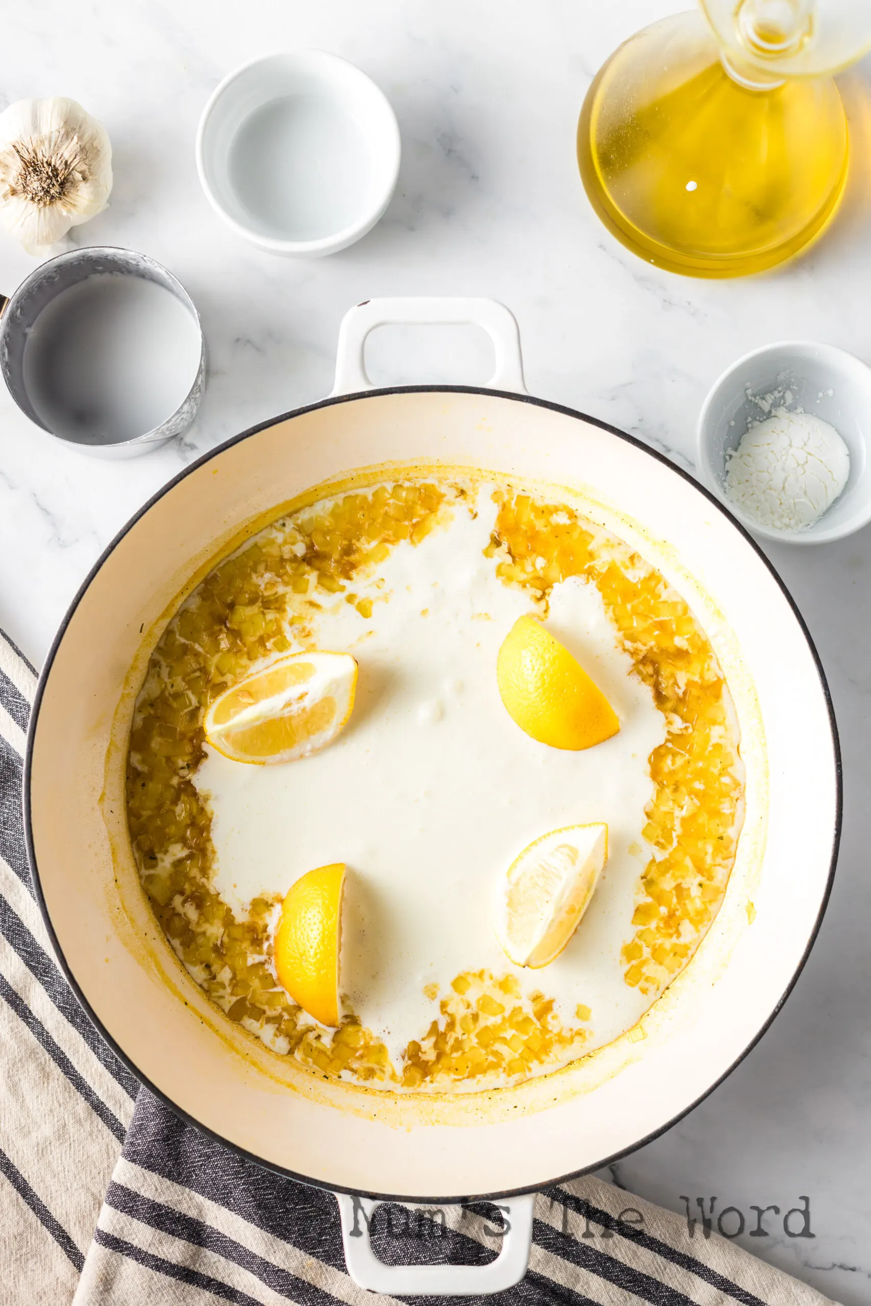 cream sauce being made in skillet with fresh sliced lemons.