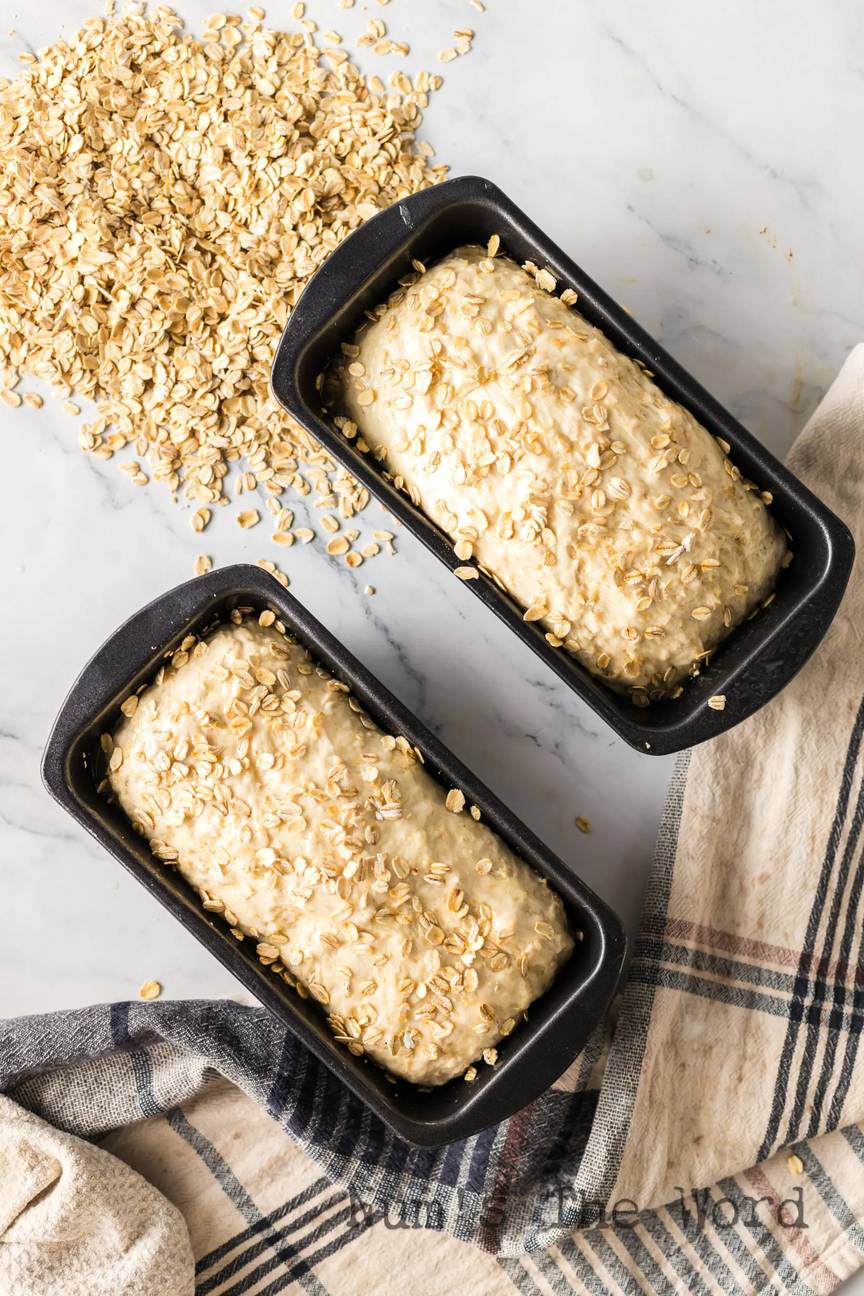 two loaves of dough in bread pans, risen but not baked.