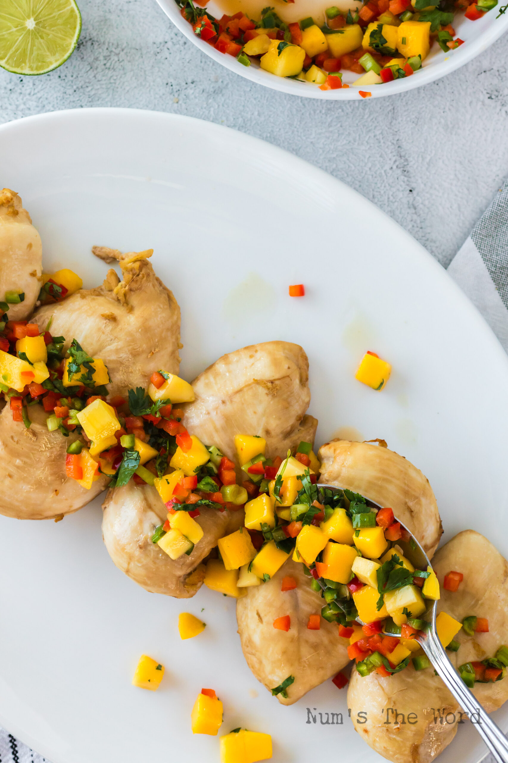 Mango salsa spread over cooked chicken breasts