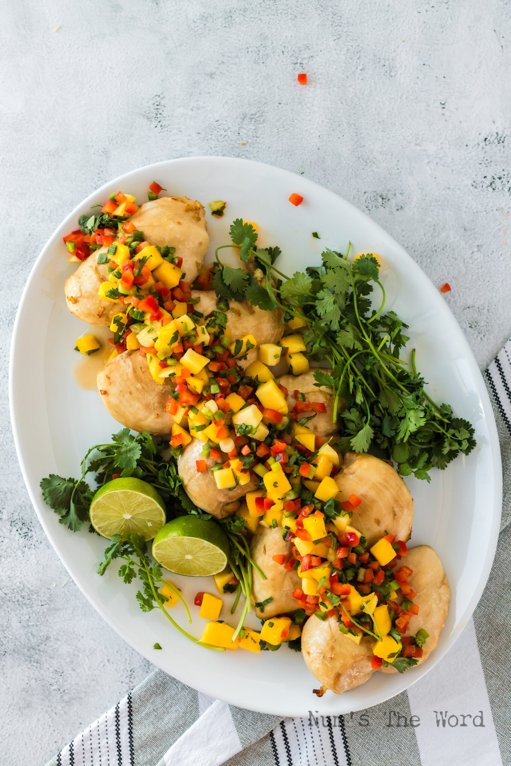 zoomed out image of salsa chicken on platter with limes and cilantro