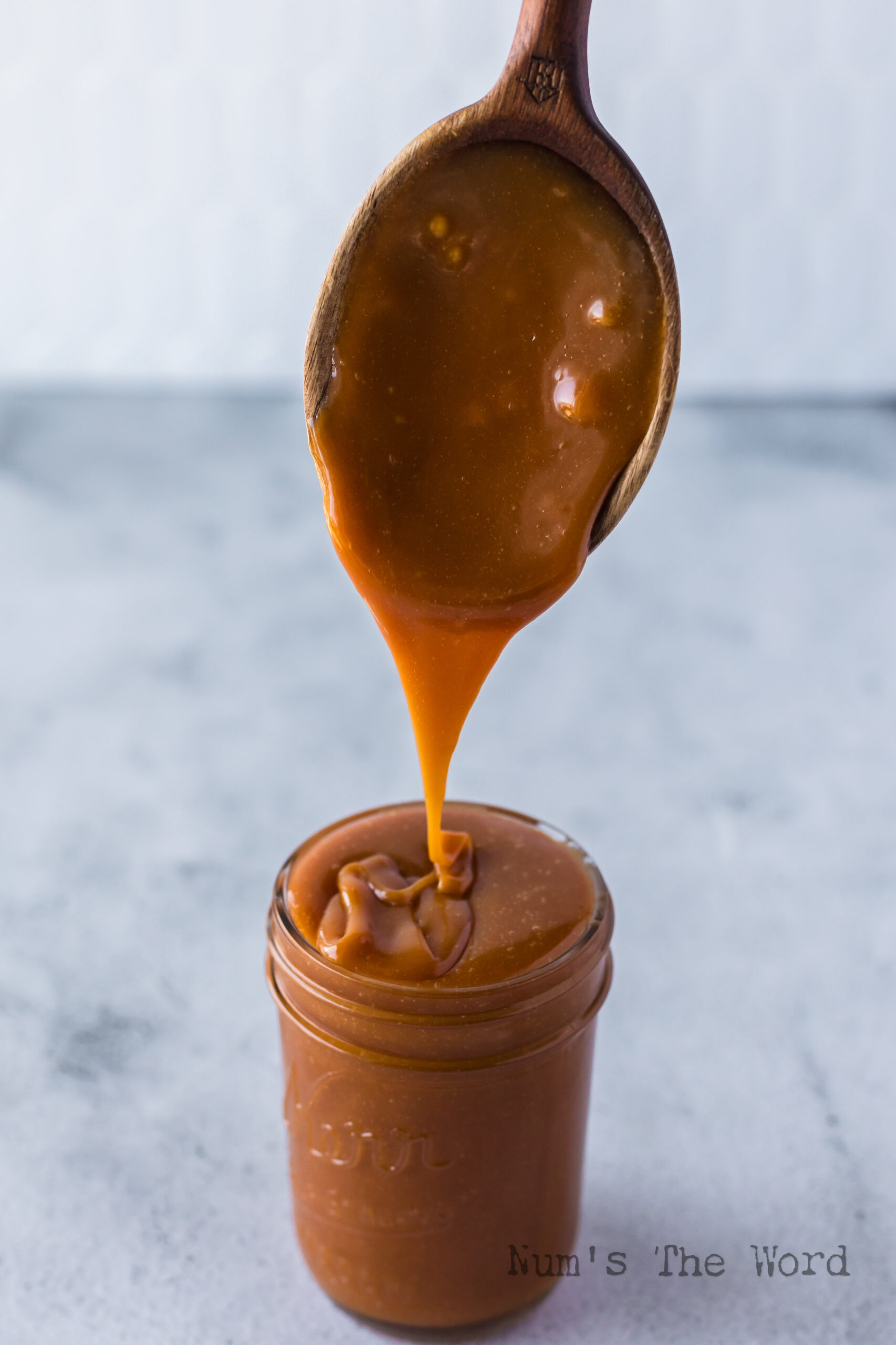 caramel sauce in jar with a spoon held over it