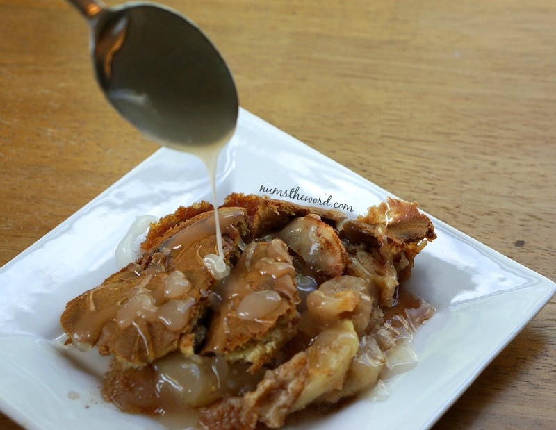 Apple Cobbler Cake - cake on a plate with a spoon over cake drizzling sauce