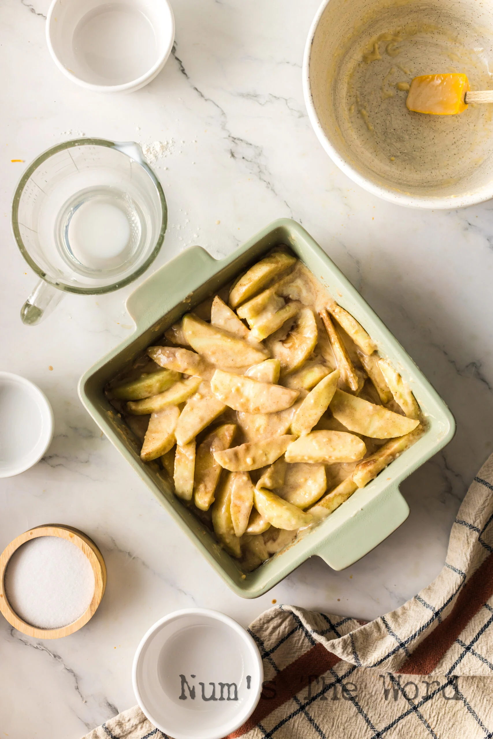 Cobbler batter poured over apples in casserole dish.